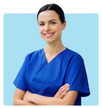 Smiling woman wearing blue medical scrubs with arms crossed, standing against a plain blue background.