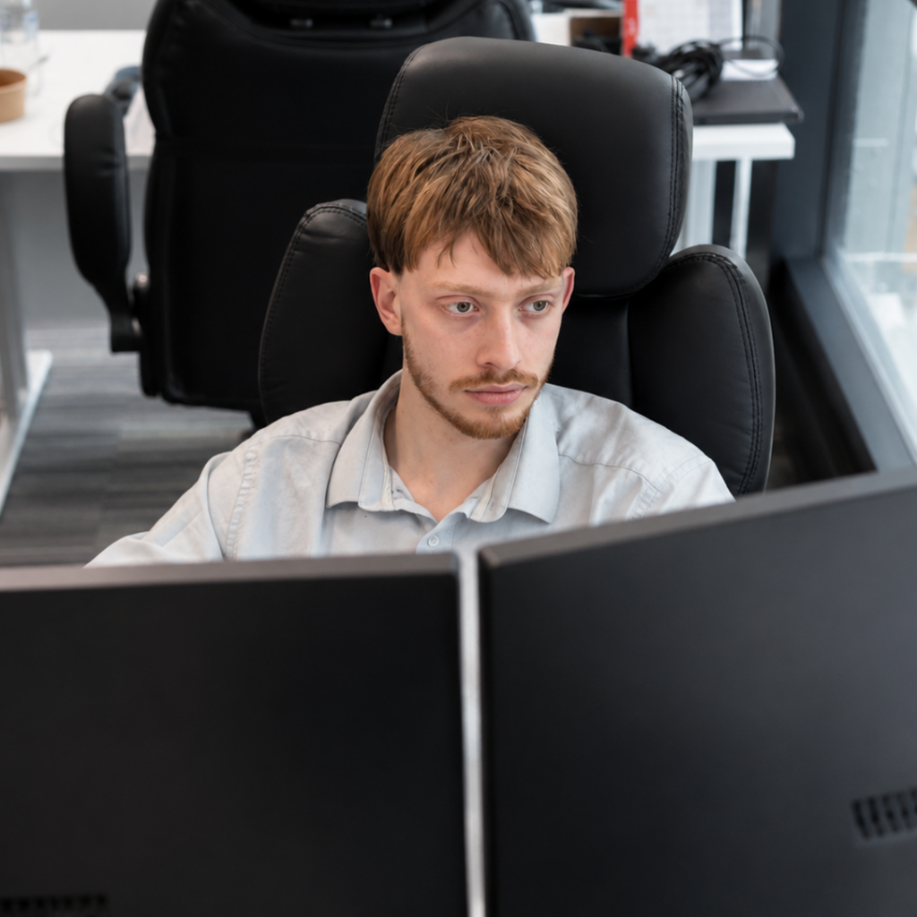 IT technician working at dual monitors in a modern office