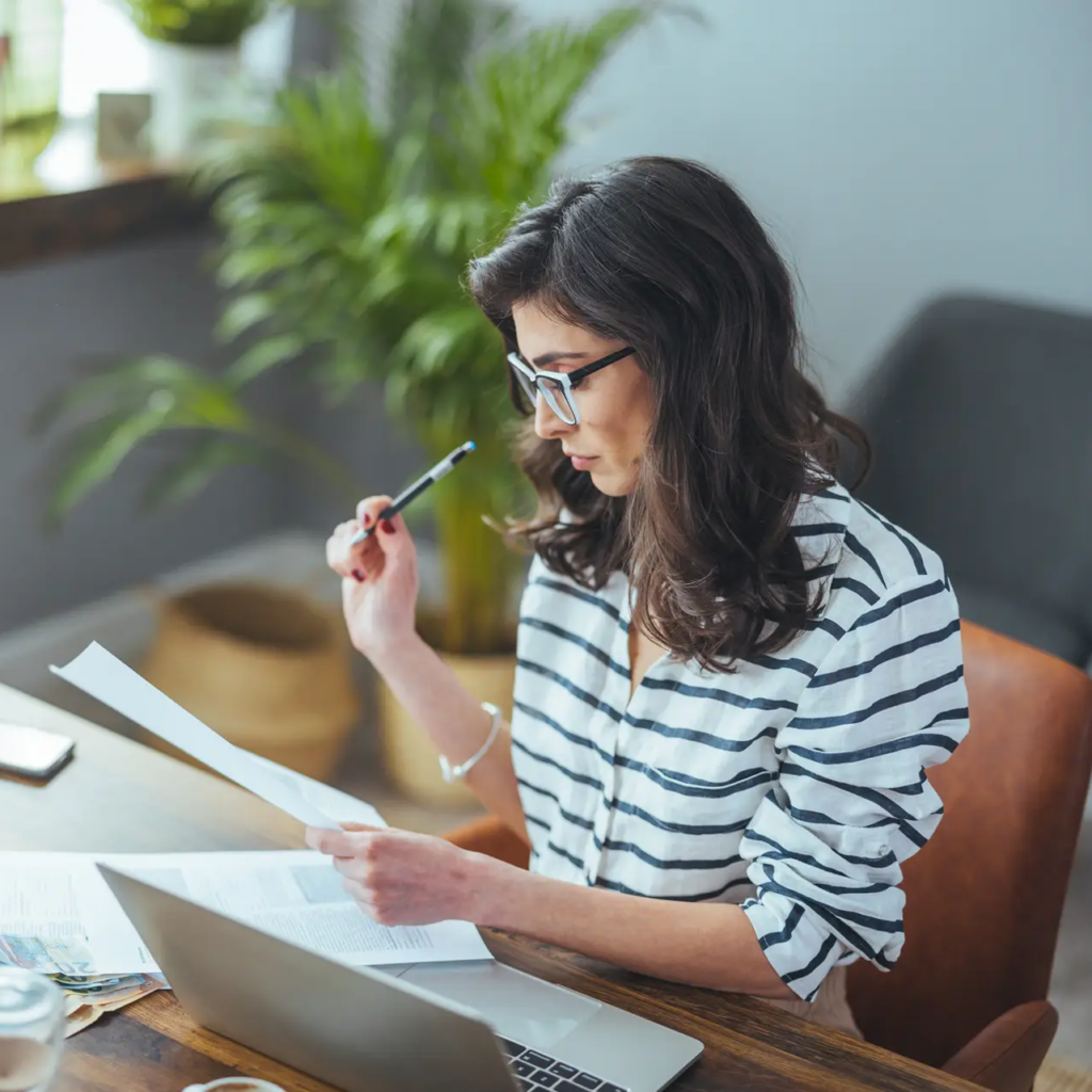 A beautiful black-haaired businesswoman sitting in her home office and filling out bills. Busy business woman. The concept of finance