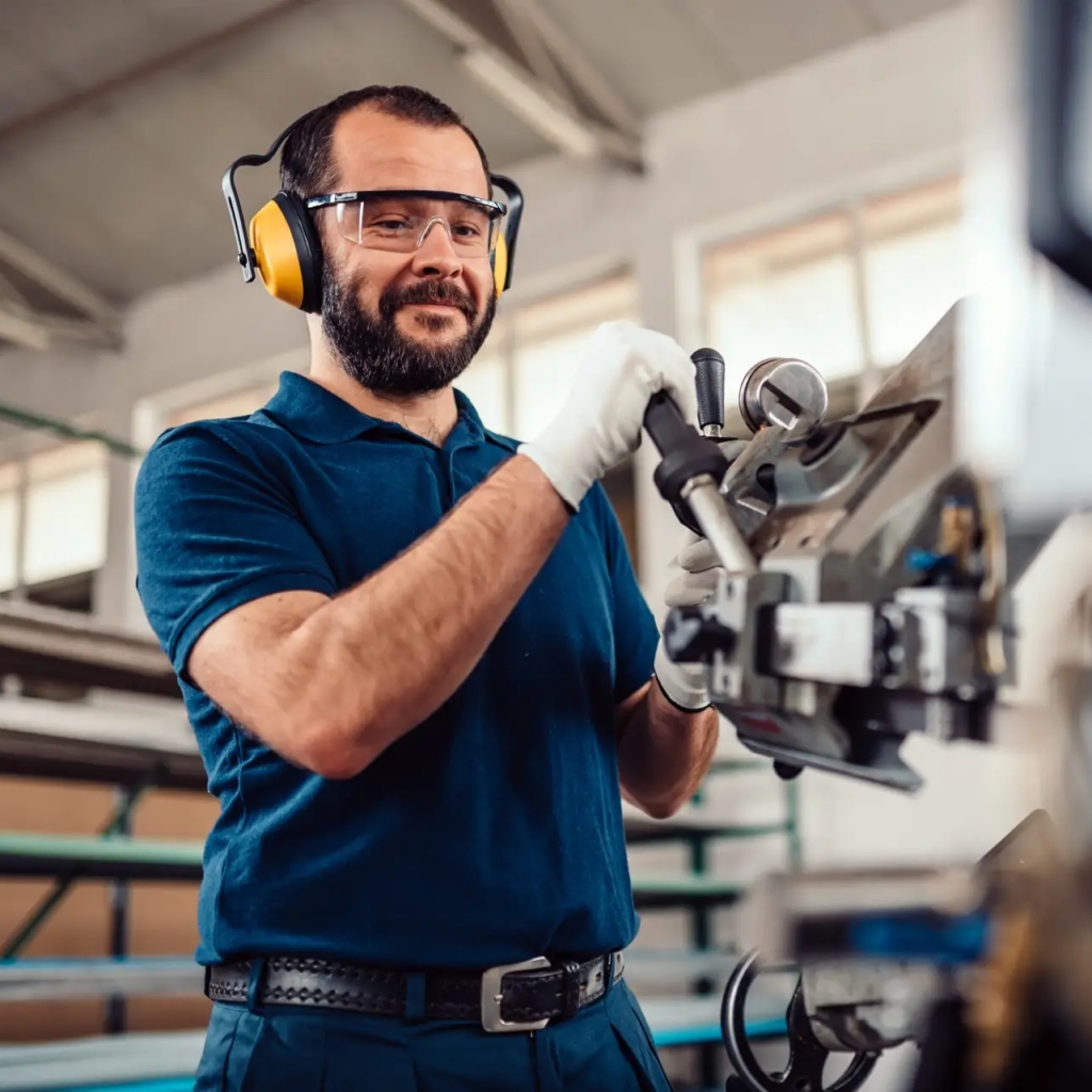 Factory worker operating band saw cutting machine for steel bars in the industrial factory